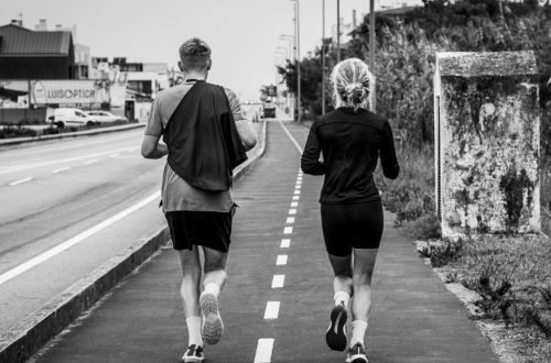 Monochrome photo of two adults jogging on an urban path, showcasing fitness and lifestyle.