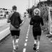Monochrome photo of two adults jogging on an urban path, showcasing fitness and lifestyle.